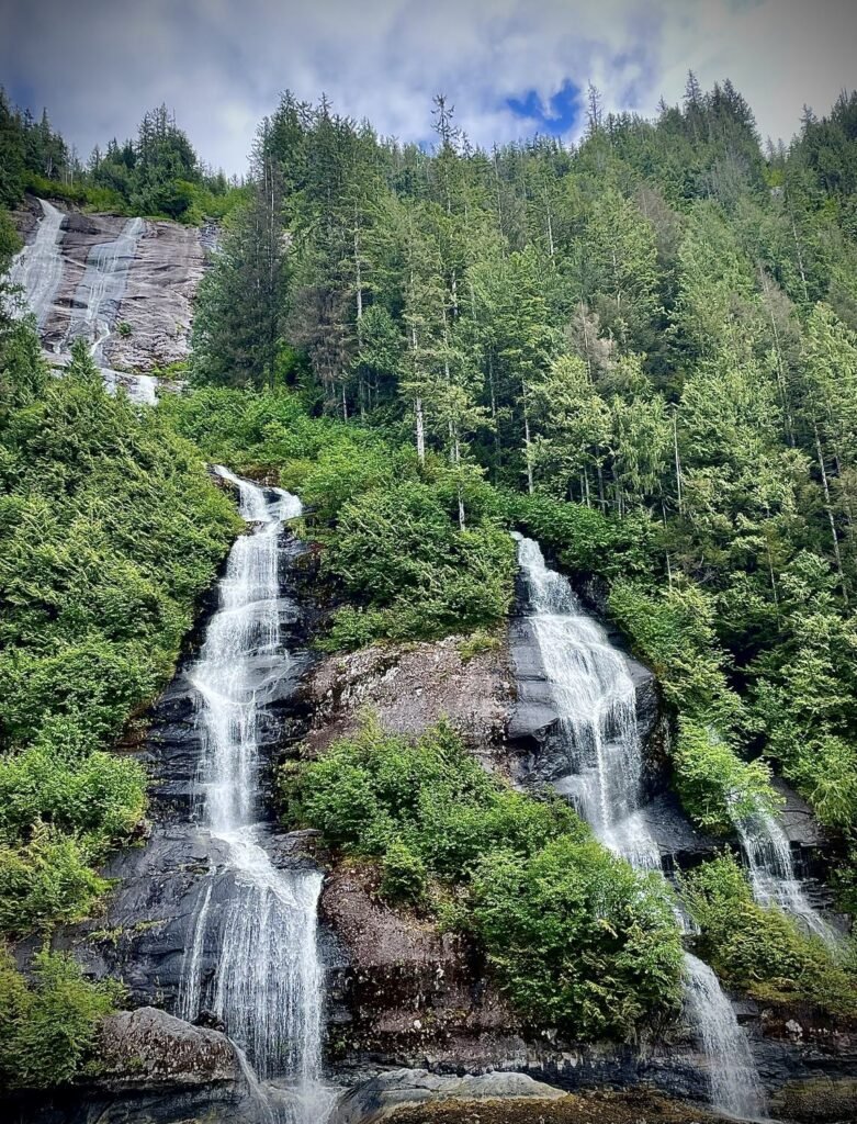 Two waterfalls tumbling through spruce forest into the water in Misty Fjords National Monument