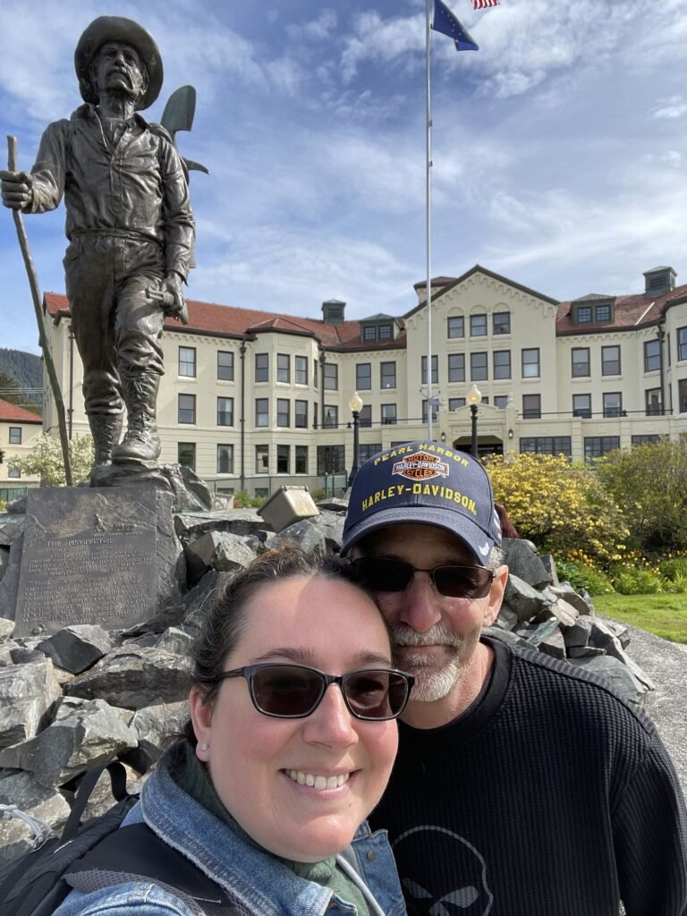 Amanda and her husband beside a statue in downtown Sitka, Alaska
